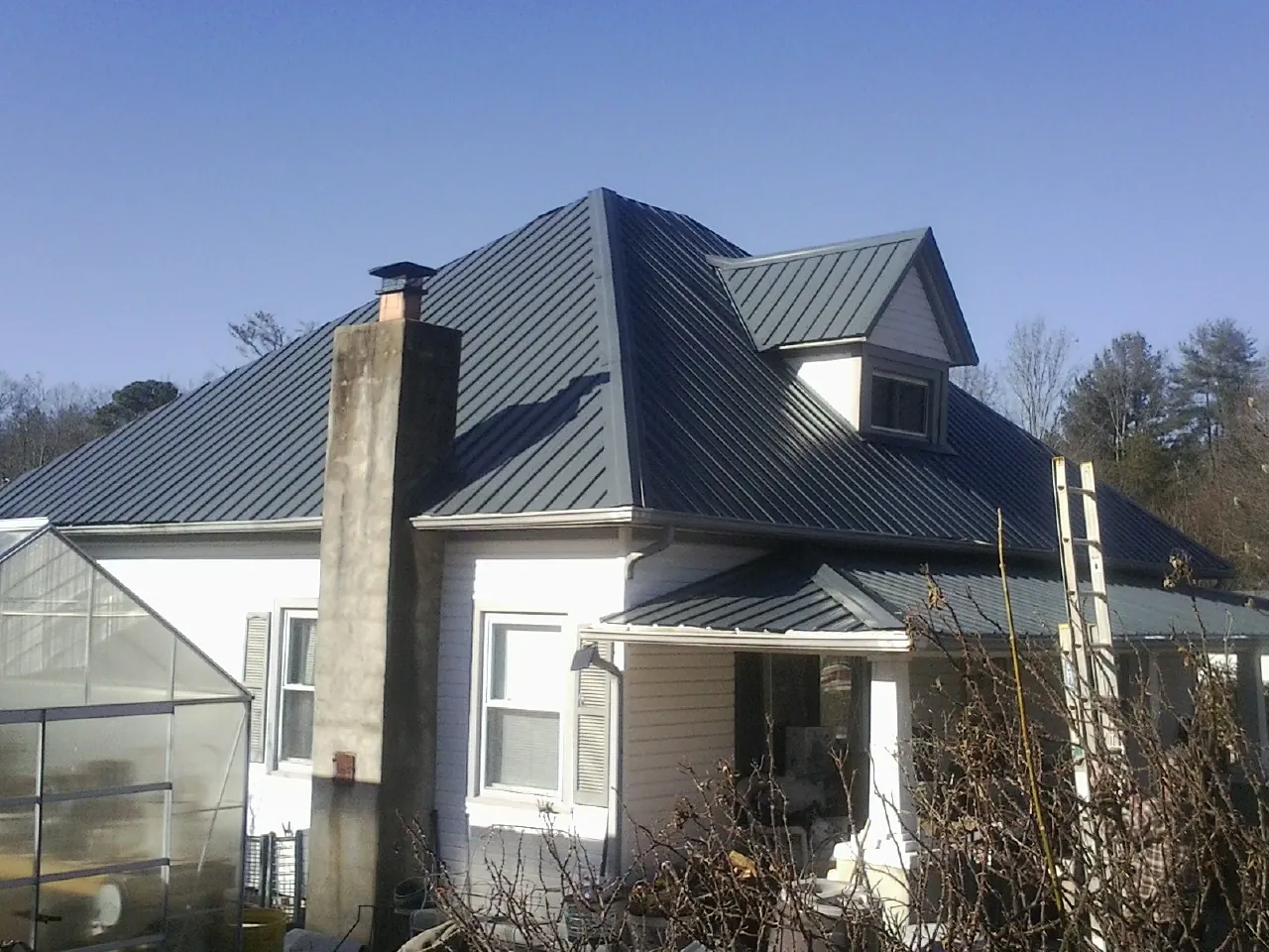 Dark blue standing seam metal roof on a white farmhouse with dormer — Slate & Tile Roof Repair by Roofing Brothers in Antimony