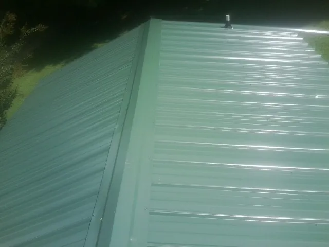 New green metal panels meeting at the ridge of a roof — Flat Roof Repair work by our crew in Antimony