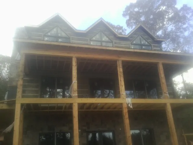 Dormers and porch framing on a large log home under construction — Roof Coating work by our crew in Antimony