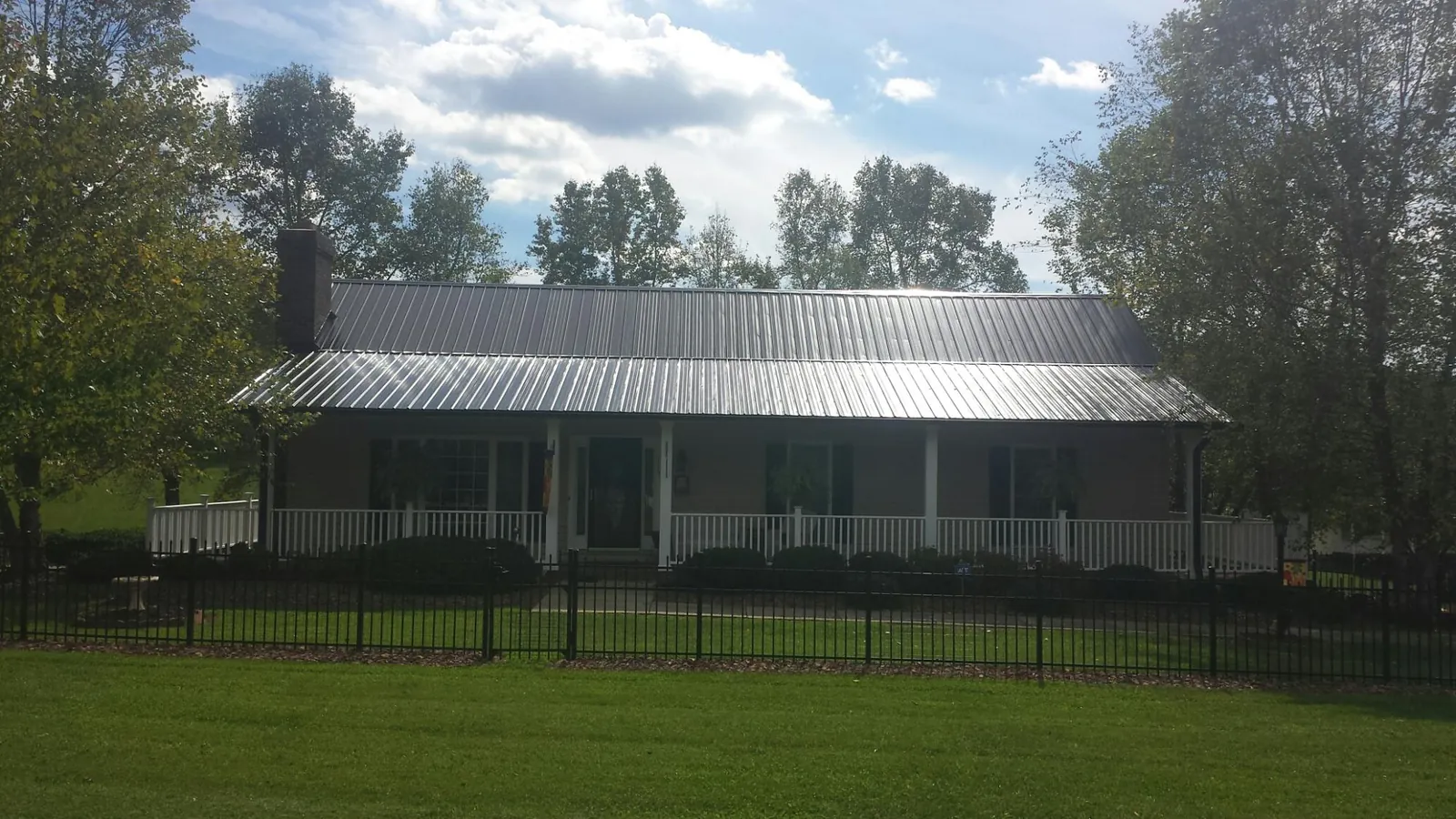 Gray metal roof on a brick ranch with a full width front porch — Gutter Guard Installation work by our crew in Antimony