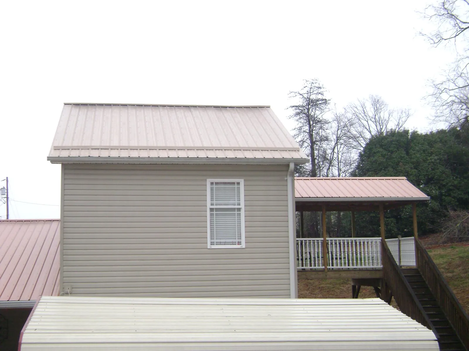 Tan metal roofs on a two story addition and attached porch, from a Roof Replacement job in Antimony