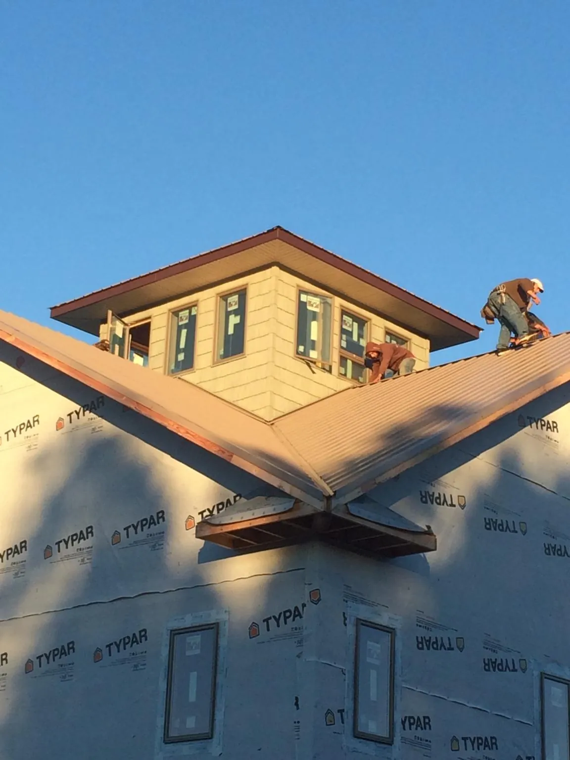 Roofers working around a rooftop cupola on a new metal roof at sunset — Roof Waterproofing in Antimony by Roofing Brothers